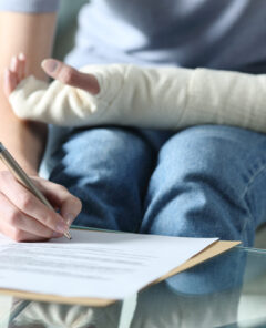 Disabled woman with bandaged arm signing document